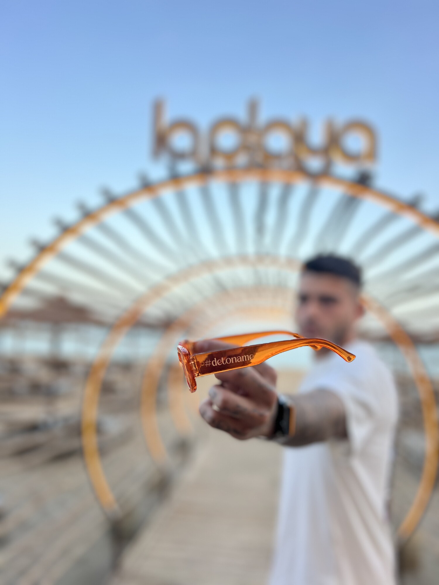 Gafas #detoname naranjas frente a un chiringuito de playa